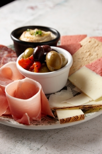 Close up of antipasto platter with cheese, crackers, prosciutto, salami and hummus - Australian Stock Image