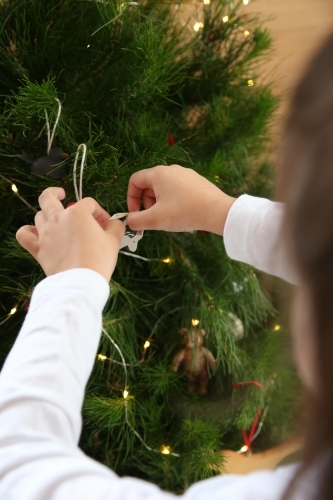 Close up of child's hands decorating Christmas tree - Australian Stock Image