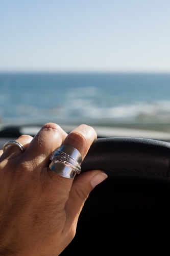 close up of female hand driving near the ocean - Australian Stock Image