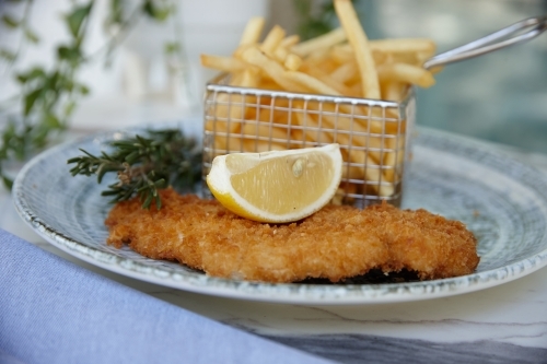 Close up of fish and chips with lemon slice on plate - Australian Stock Image