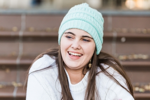 Close up of girl smiling looking away wearing beanie - Australian Stock Image