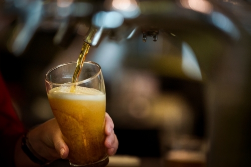 Close up of glass with on tap drink pouring into glass at pub - Australian Stock Image