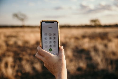 Close up of hand and smartphone in paddock - Australian Stock Image