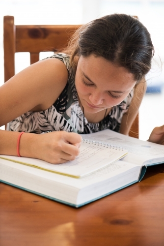 Close up of teenager doing homework at table. - Australian Stock Image