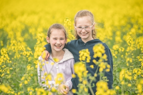 Close up of two sisters in their family canola field. - Australian Stock Image