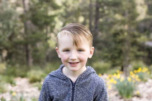 Close up of young boy in the bush, smiling at the camera - Australian Stock Image