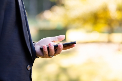 Close up of young businessman holding mobile phone - Australian Stock Image