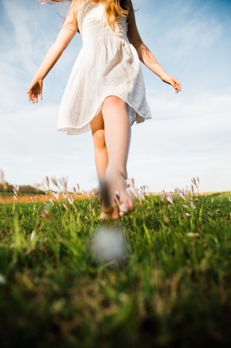 Close up of young girls legs walking in a field of flowers