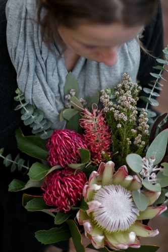 Close up of young woman holding a bouquet of native flowers - Australian Stock Image