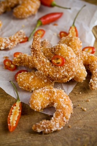 Close up shot of a fried shrimp with white sprinkles on  it and a chopped chili around it - Australian Stock Image