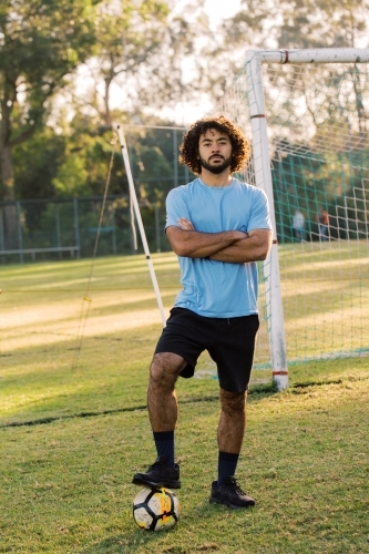 Close up shot of a man standing on the field with a ball on his left foot - Australian Stock Image