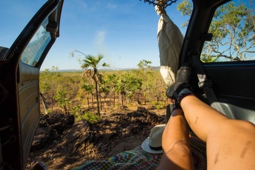 Close up shot of a woman lying down in her car with a view of sky trees and land - Australian Stock Image