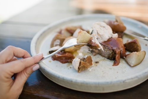 Close up shot of a women's hand about to devour a dessert on a serving platter - Australian Stock Image