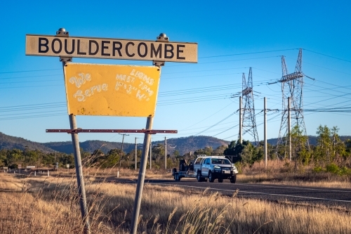 Close up shot of a signage on the roadside and a highway with a car - Australian Stock Image