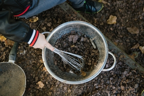 Close up shot of dirt and stones in a silver pale being mixed with an egg beater - Australian Stock Image