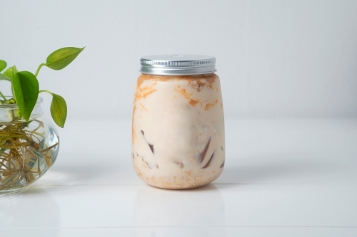 Close up shot of peanut butter protein smoothie in a jar with a plant on the side - Australian Stock Image