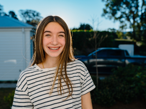 Closeup of a young teenage girl smiling at the camera. - Australian Stock Image