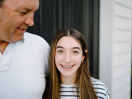 Closeup of a young teenage girl standing beside her dad. - Australian Stock Image