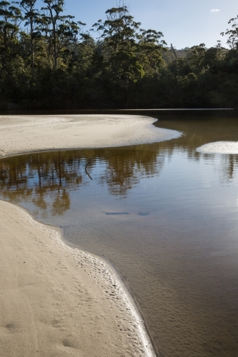 Coastal lagoon with sand and water and distant trees - Australian Stock Image