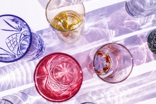 Coloured glasses on purple with light shining in shadows - Australian Stock Image