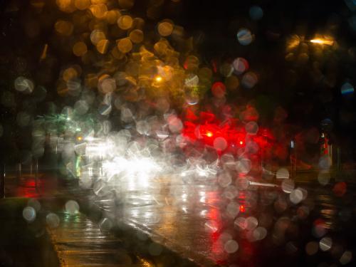 Colourful city light patterns distorted by rain on a car windscreen - Australian Stock Image