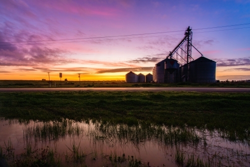 Colourful dawn with water reflections and silo silhouettes. - Australian Stock Image