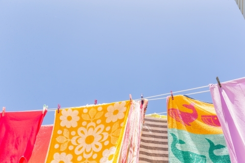 Colourful towels and swimmers hanging on washing line - Australian Stock Image