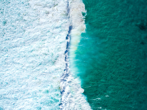 Colours in the wet setting are separated by white wash and still ocean - Australian Stock Image