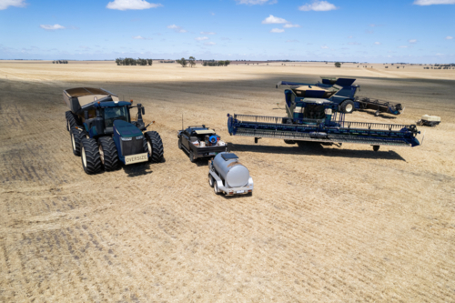 Combine harvester and tractor parked on the crop field - Australian Stock Image