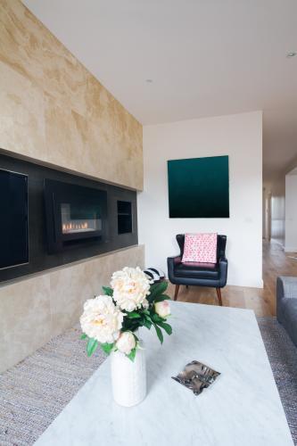 Comfy leather armchair with pink cushion in living room with flowers on coffee table