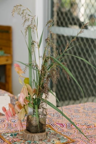 Common reed grass and lilly pilly leaves in a small container with water and rocks - Australian Stock Image