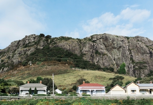 Continuous wooden fence in front of houses with rocky mountain in background