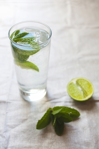 Cool glass of water with ice and mint on tabletop - Australian Stock Image