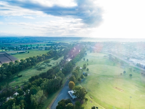 cool morning light over green sports field in recreational park area beside hunter river in town - Australian Stock Image