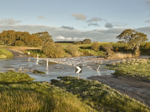 country road leading through flooded causeway - Australian Stock Image