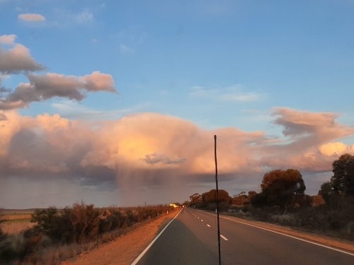 country road with sunlit clouds in distance - Australian Stock Image