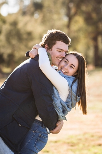 Couple cuddling arms wrapped tight smiling