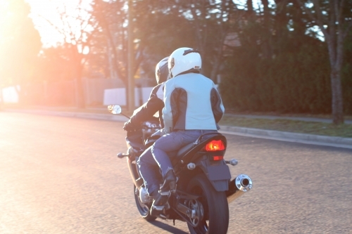 Couple riding a motorbike on a suburban street - Australian Stock Image