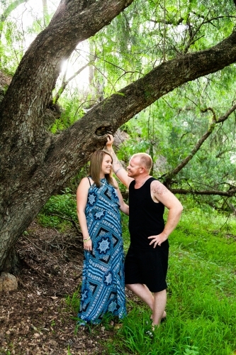 Couple standing together outside under willow tree - Australian Stock Image