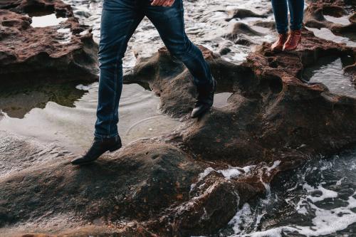 Couple walks over rockpools - Australian Stock Image