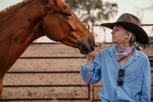 Cowgirl patting horse - Australian Stock Image