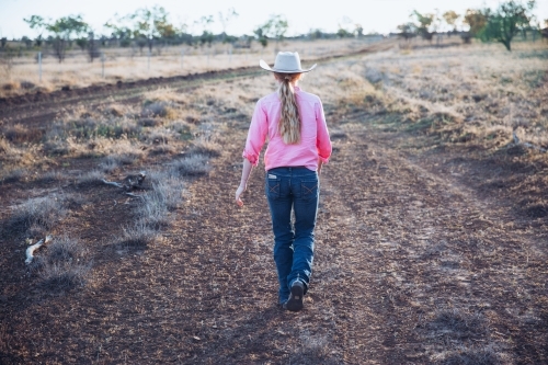 Cowgirl walking on dirt track