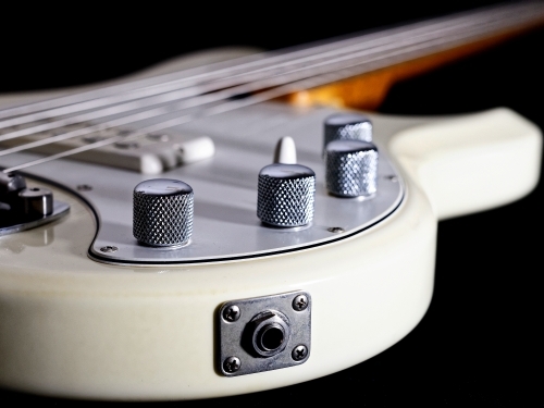 Cream white electric bass guitar showing strings side view - Australian Stock Image