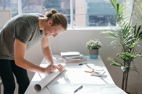 Creative guy addressing a mailing tube to send by post - Australian Stock Image