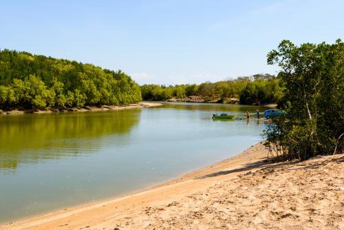 Creek scene with beach and men with vehicle  launching boat on boatramp - Australian Stock Image