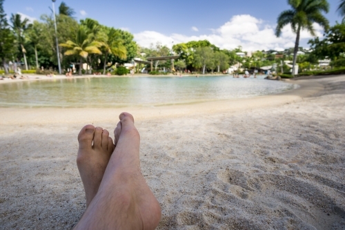 Crossed feet in foreground of Airlie Beach Lagoon - Australian Stock Image