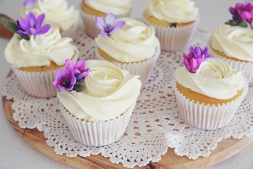 Cupcakes with purple edible flowers for tea party - Australian Stock Image