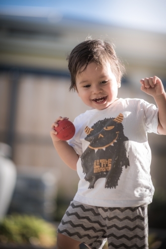 Cute 1 year old boy takes his first steps outside in his suburban backyard - Australian Stock Image