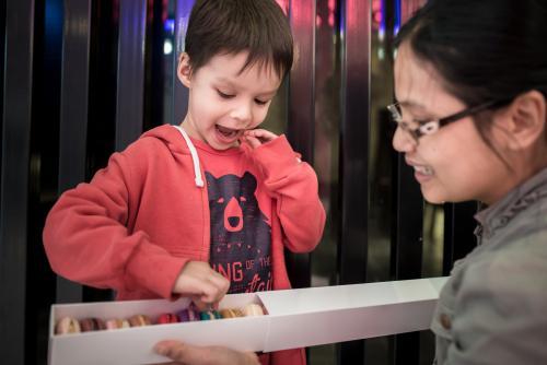 Cute 4 year old mixed race boy chooses a macaron treat - Australian Stock Image