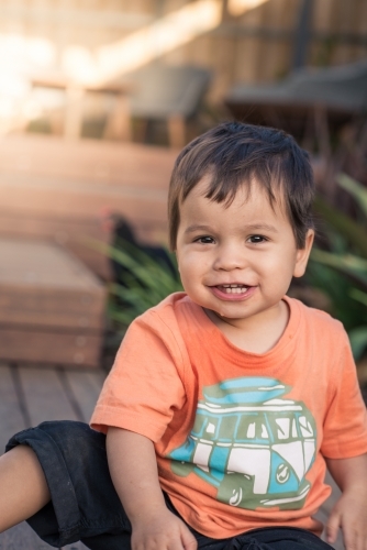 Cute mixed race 1 year old baby boy plays happily in his suburban backyard - Australian Stock Image